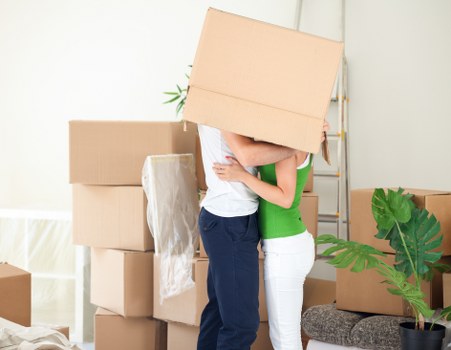 Removalists carrying furniture through a London flat staircase